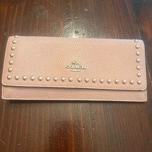 Light pink Coach wallet with gold button looking shapes bordering the front.